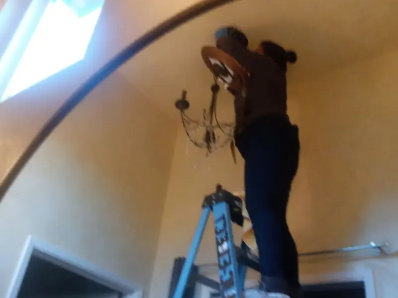 Electrician installing a chandelier in a North Valley residence